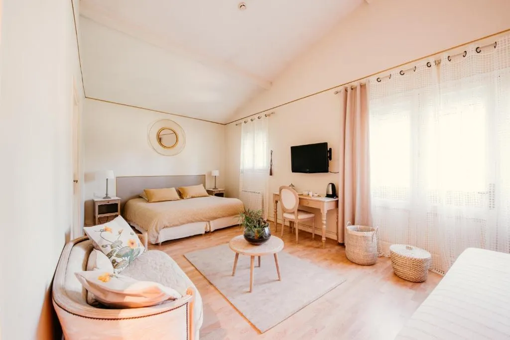Chambre Cybele lumineuse avec lit double, coin salon et grandes fenêtres.