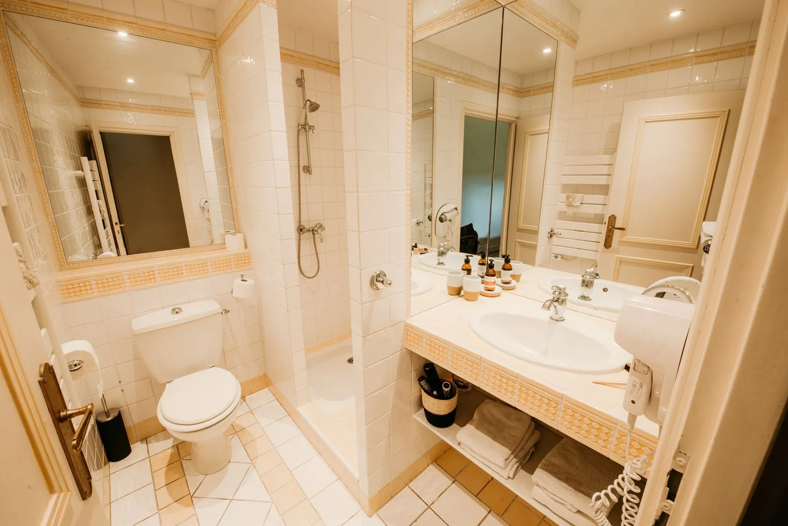 Salle de bain ivoire de la chambre Ceres avec douche, vasque et grands miroirs.