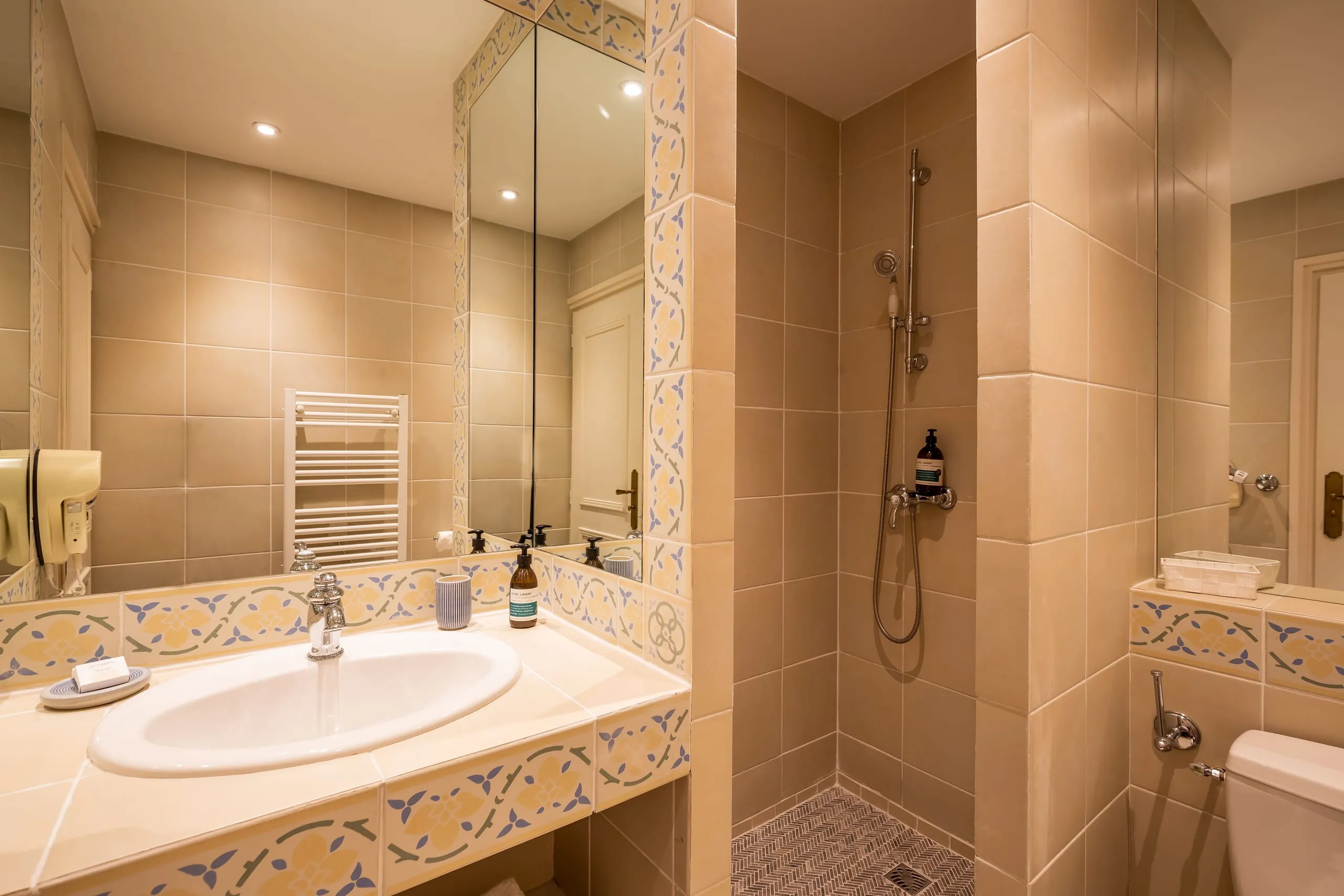 Bathroom of the Luna room with a shower, a washbasin and decorative beige and blue tiles.