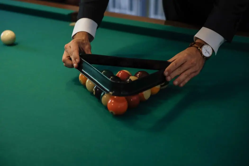 A player setting up the balls on the green-baize billiard table at Le Clos de Meyre.