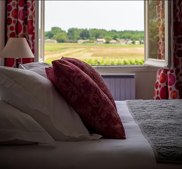 Bed in a room at Le Clos de Meyre with a window open onto the vineyard in Avensan.