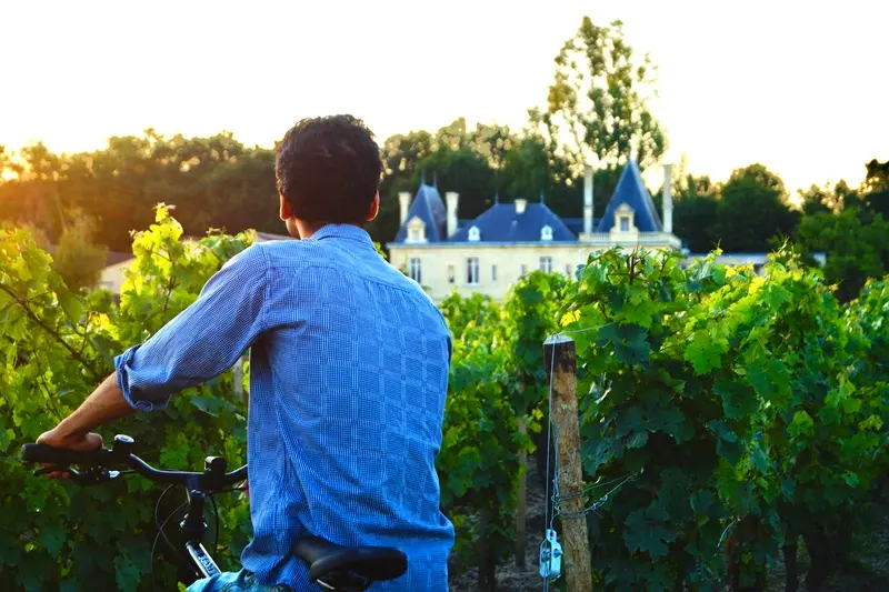 Cycliste dans les vignes face au Château Meyre lors d’une découverte du vignoble à vélo.