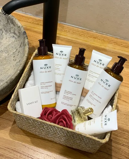 Panier de produits d’accueil NUXE Rêve de Miel près d’une vasque en pierre au Clos de Meyre.