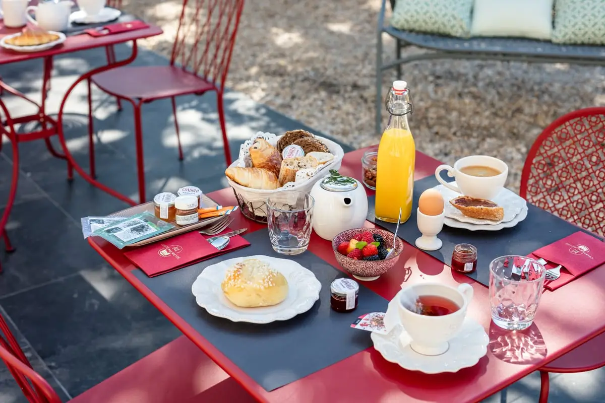 Petit-déjeuner avec viennoiseries, fruits rouges, œuf et jus de fruits servi en terrasse au Clos de Meyre.