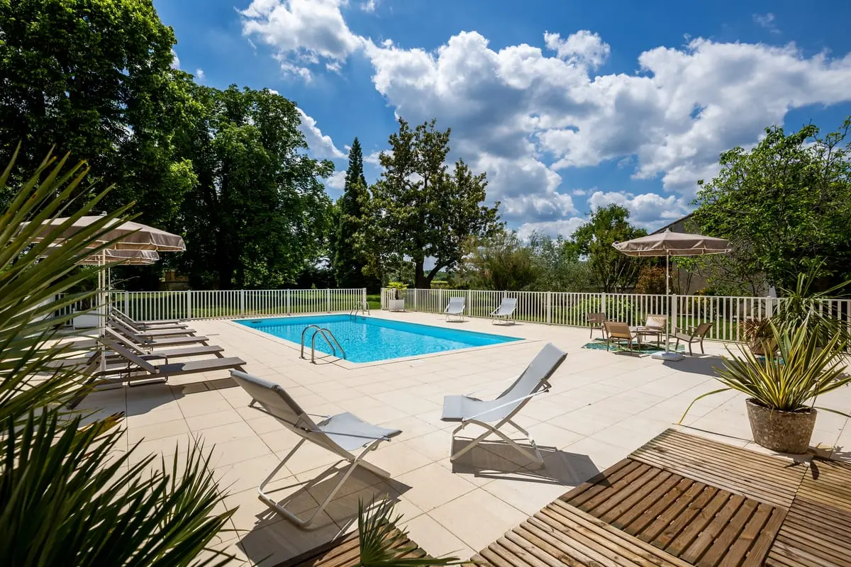 Piscine extérieure du Clos de Meyre à Avensan, entourée de transats et d’un parc arboré.
